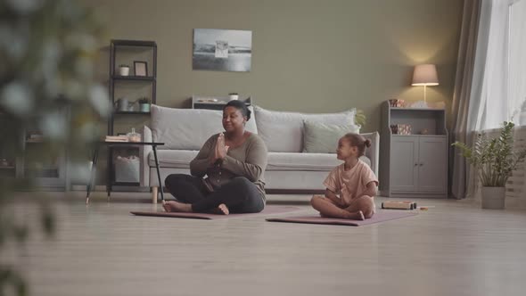 Mom and Little Daughter Meditating Together at Home