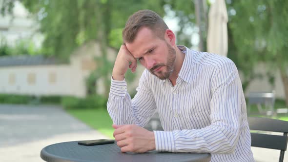 Middle Aged Man Feeling Worried While Thinking in Outdoor Cafe