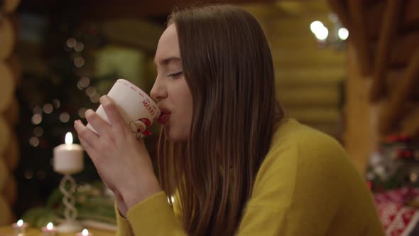 Young girl smiling and drinking from a mug