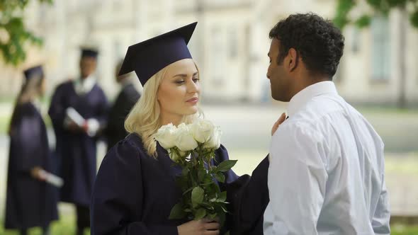 Female Graduate in Academic Regalia with Flowers Talking to Boyfriend, Education