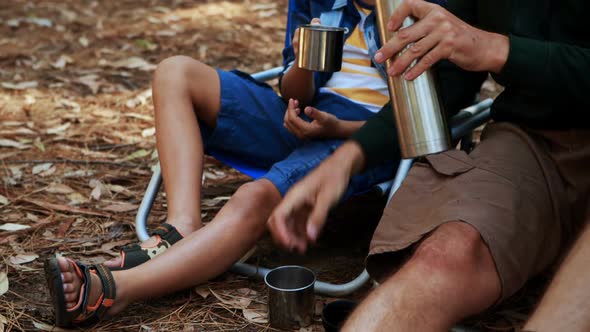 Father and son having coffee outside tent