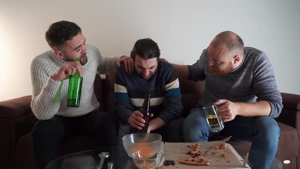 Unhappy Stressed Guy Drinking Beer Sitting on Sofa with Friends