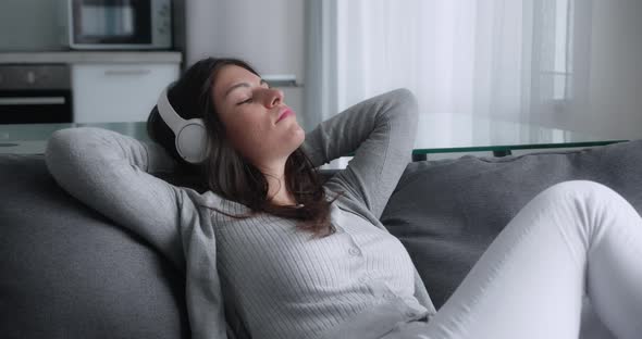 Calm Young Woman in Headphone Having Healthy Daytime Nap Dozing Relaxing on Couch with Eyes Closed
