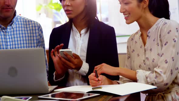 Group of business executives discussing over laptop at their desk