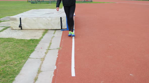 Low section of female athlete measuring high jump field with footstep 4k