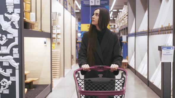 Woman choosing some stuff in hardware store. Pushing shopping cart buying materials in house improve