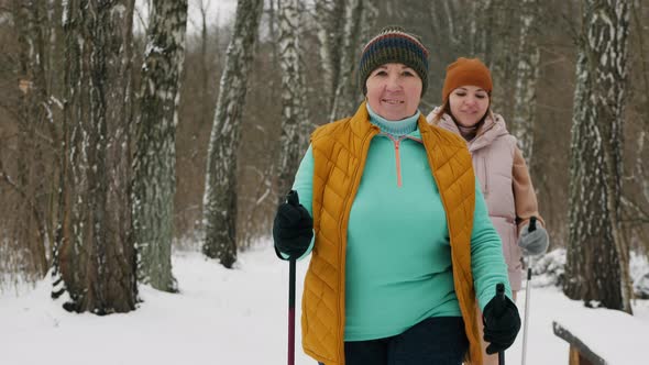 An Elderly Woman with Her Middleaged Daughter Are Engaged in Nordic Walking in the Winter