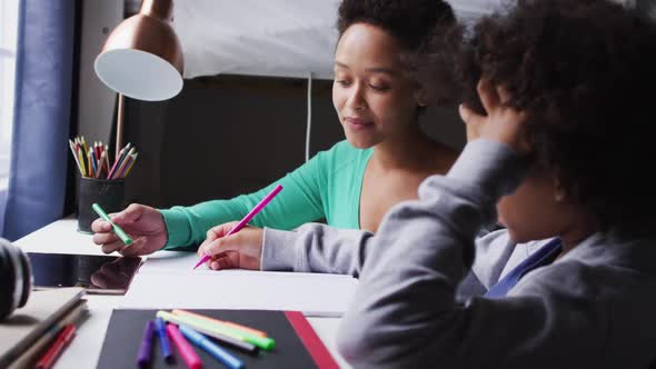 Mixed race mother and daughter drawing in a notebook