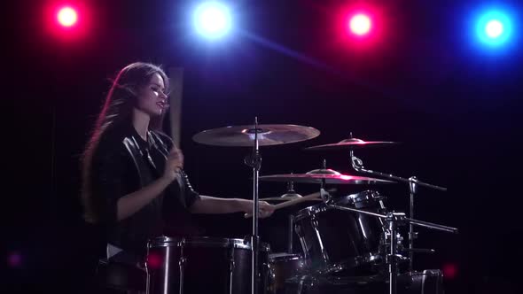 Girl Is Playing the Drums. Black Background. Red Blue Light From Behind. Side View. Slow Motion