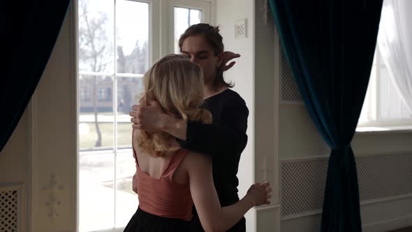 Young Blonde Woman and Her Boyfriend are Dancing and Embracing Natural Sunlight Indoors