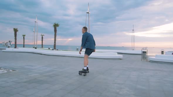 a Young Caucasian Man Roller Skating with Quad Skates Near the Sea Slow Motion