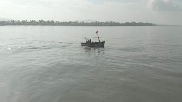 profile follow Drone shot of small colourful Indian fishing boat going out to sea looking towards sh