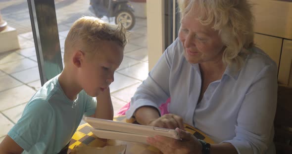 Grandmother and Grandson with Pad in Cafe