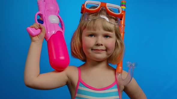 Little Girl with Short Hair in Swimsuit with Pink Water Gun Smiles in a Studio