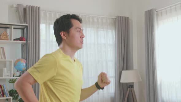 Side View Of Asian Man Running On A Treadmill At Home