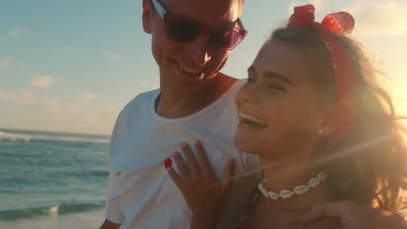 Young Caucasian Man and Woman Hugging Each Other Walking Along Ocean Beach