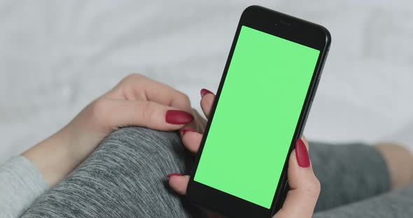 Woman Sitting on the Bed and Holding Smartphone with Prekeyed Green Screen