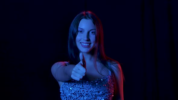 Portrait of Charming Young Woman Is Looking at Camera Smiling Shows Thumbs Up Gesture. Close Up