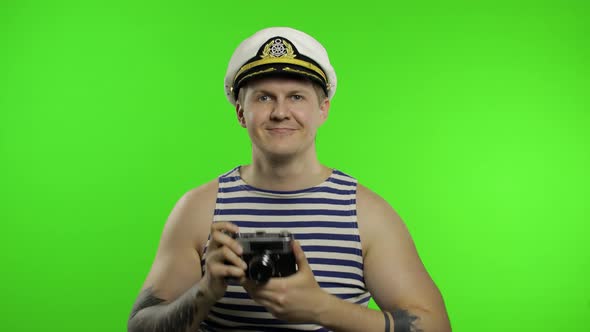 Young Sailor Man Takes a Photo on a Retro Camera. Seaman Guy in Sailor's Vest