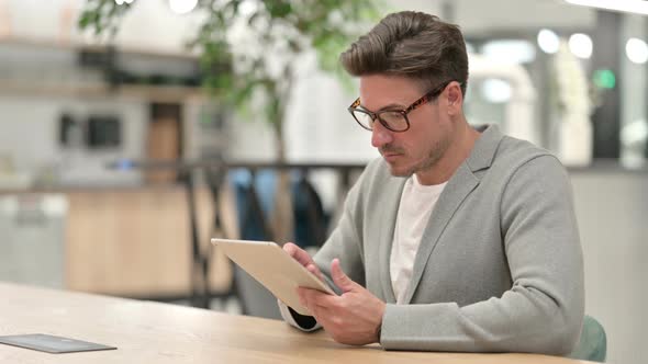 Pensive Middle Aged Man Using Tablet in Office 