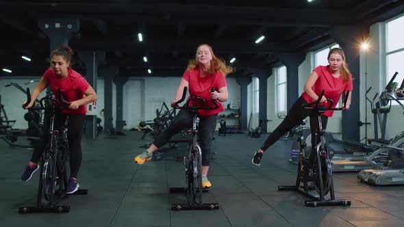 Athletic Women Group Riding on Spinning Stationary Bike Training Routine in Gym Weight Loss Indoors