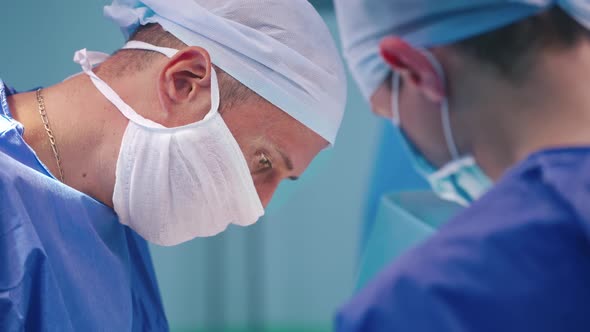 Surgery team in operating room. Side view of surgeon performing operation
