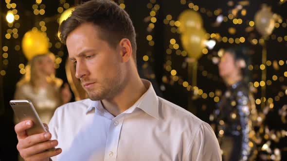 Young Man Messaging Smartphone at Party Closeup, Ordering Taxi by Application