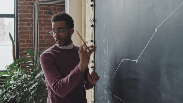 Man Explaining Graph on Blackboard