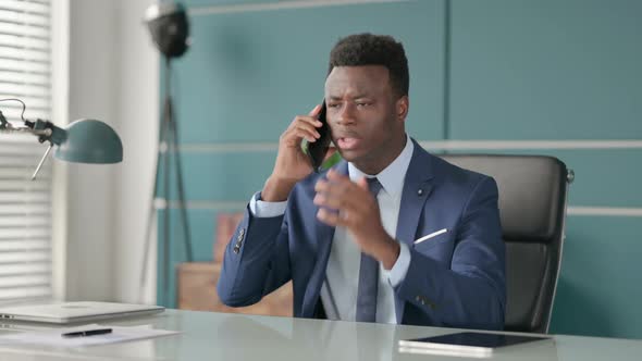 Angry African Businessman Talking on Smartphone in Office