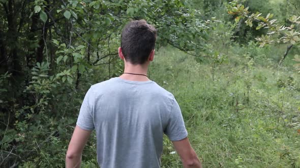 Young Man Walking in The Forest, Summer time. close up shot from the back