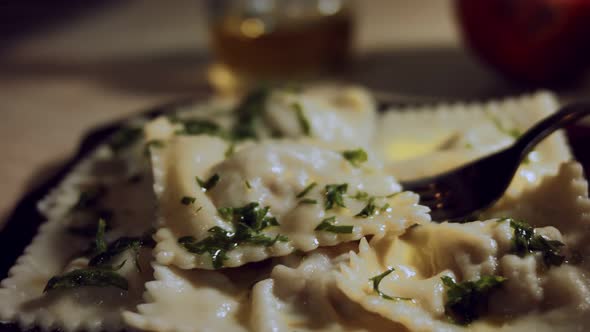 Closeup of Fork Taking Ravioli Covered with Melted Butter and Chopped Parsley