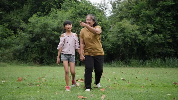 Slow motion of Happy grandmother with granddaughter playing in the park