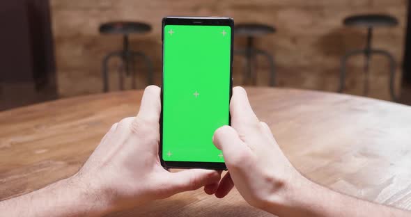Static Shot of Male Hands Holding a Phone with Green Screen Display
