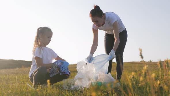 Volunteer Team Family Picking Up Trash and Plastics Cleaning the Park with a Garbage Bag. Teamwork