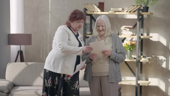 Two Positive Senior Retirees Talking Looking at Photos Smiling