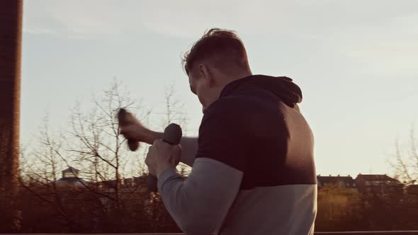 Young and fit man having evening workout outdoor. Urban sunset background.