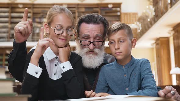 Old Man Reading Book, Raised Finger that His Teenage Grandchildren Understand the Contant of Book