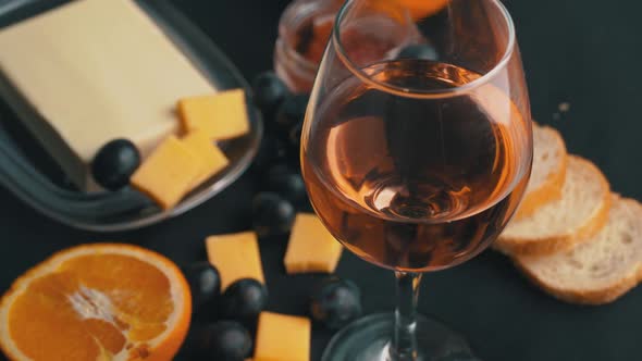 A Glass of Rose Wine Swirls With Appetizers