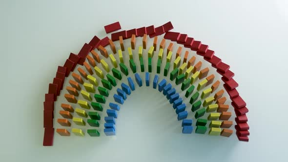 Line up of Dominoes in Slowmotion Rainbow Falling Colors with LGBT Colors of a Hand