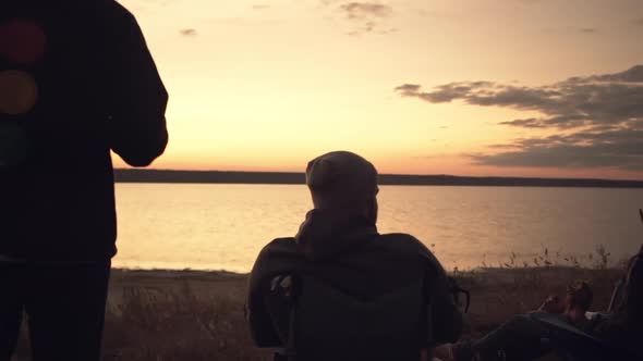 Group of Friends Watching Sunset Camping Together Near Water