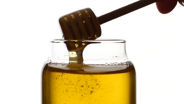 Glass Jar of Honey with Wooden Drizzler, Pick It Up, Isolated on White, Slow Motion, Close Up