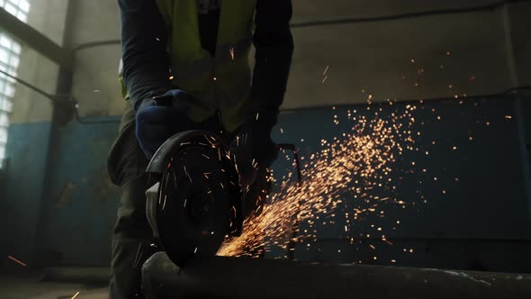 Close Up of Construction Worker Cuts Steel with a Circular Saw Construction Worker's Feet Flying