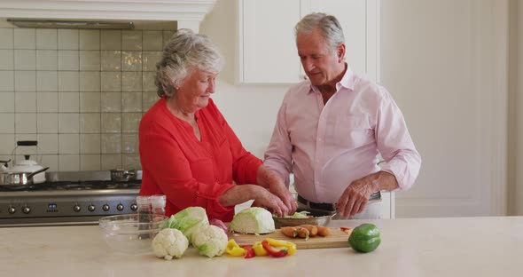 Caucasian senior couple smiling while looking at each other in the kitchen at home