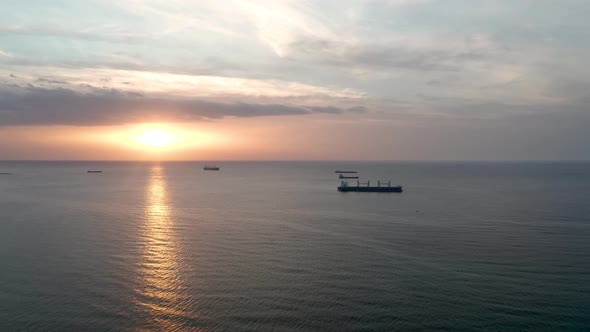 A drone flight around container ships into the sea at sunrise