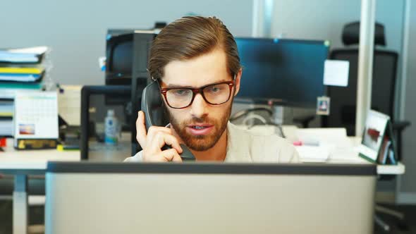 Male executive talking on telephone at desk