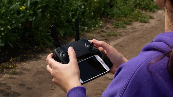 Remote control of the drone in the close-up. Women controlling flying drone for aerial view.