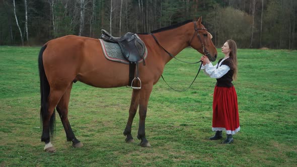 Beautiful Female in a Medieval Dress Stands in a Field Next to a Horse  Slow Motion