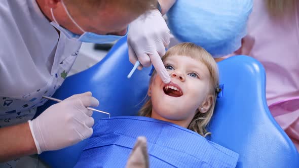 Little child in stomatology chair points at the ill tooth with a finger - close up video.