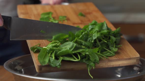 Hands Pour Sliced Spinach From a Chopping Board Into a Metal Bowl Making a Vegetable Salad