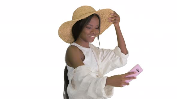 Smiling African American Woman in a Straw Hat Taking Selfie While Walking on White Background